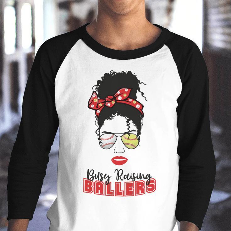 Baseball Busy Raising Ballers Momlife Mom Messy Bun Afro Mom Mothers Day Youth Raglan Shirt